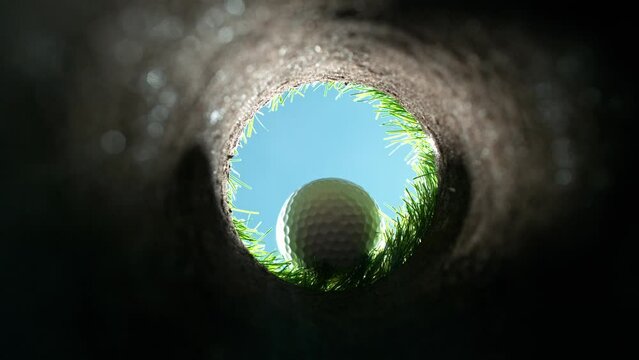 Super slow motion of golf ball falls into the hole at the camera, view inside the hole close-up. Filmed on high speed cinematic camera at 1000 fps.