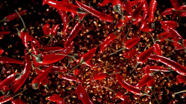 Super slow motion of exploding chilli peppers isolated on black. Overhead view, filmed on high speed cinema camera, 1000 fps. Ultimate perspective and concept of flying food.