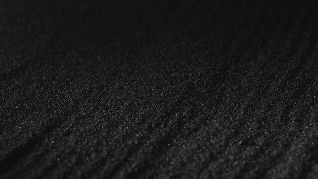 Black sand falling on ground. Textured abstract natural backdrop. Dark dust, volcano powder, gunpowder covering surface