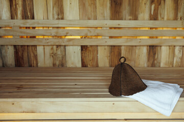Bath hat and white towel on wooden boards in the sauna