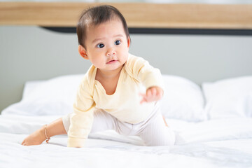 Fototapeta premium Asian baby girl with white skin and big eyes naughty age playing on the bed by the bedroom window