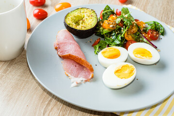 Plate with a keto diet food. Eggs, vegetable salad with tomatoes, bacon and avocado. Keto breakfast.