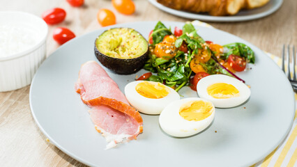 Plate with a keto diet food. Eggs, vegetable salad with tomatoes, bacon and avocado. Keto breakfast.