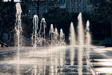 fountain in the rays of the sun in a modern park in the city - obrazy, fototapety, plakaty