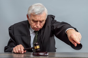 Judge banging judge's gavel, index finger pointing. Law Lord wearing gown using a hammer for...