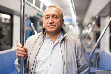 Fototapeta na wymiar Mature man standing in subway and holding handrail