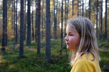 Blonde girl in a forest, side view portrait, autumn nature, copy space