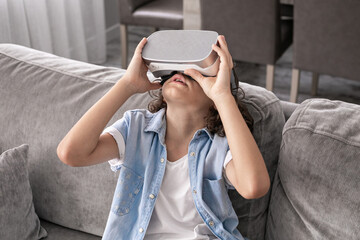 Obraz premium close up happy little boy child using virtual reality headset vr glasses gesturing at home fun