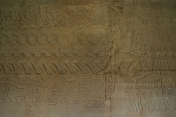 Fototapeta na wymiar The low relief sandstone carvings tell the story of Hindu Brahmin beliefs between angels and devils on the walls of Angkor Wat Siem Reap, Cambodia.