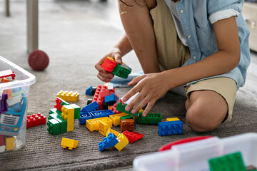 Little toddler boy playing with colorful plastic blocks at home building creative game, imagination