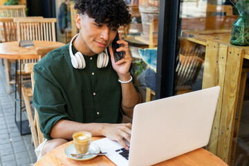 Smiling young man working on laptop in cafe