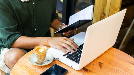 Anonymous young man with laptop in cafe