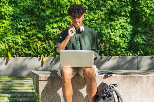 Ethnic male student with laptop in park