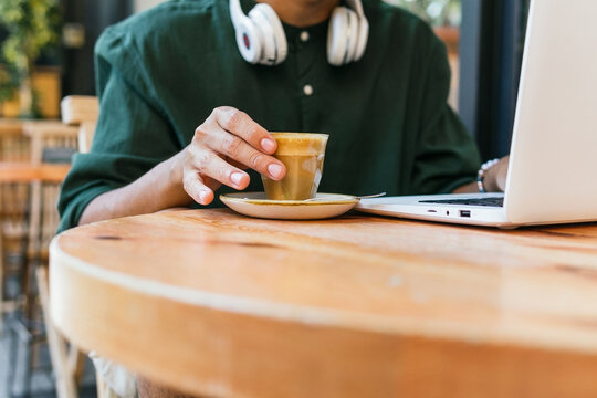 Anonymous young man with laptop in cafe