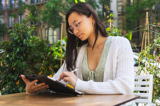 Asian woman browsing tablet in outdoor cafe
