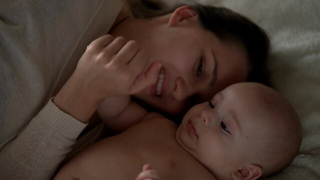 Newborn Baby With Young Mom look Into Each Other Eye. Cute Smiling Teethless Kid Face Portrait. Woman Kissing With Child Look At Camera. Infant, Mother Day, Childbirth, Beginning, Relationship Concept