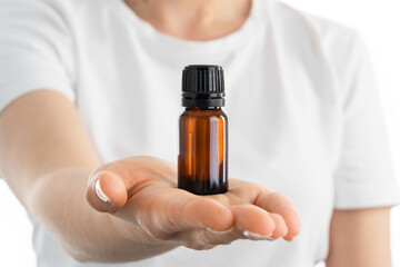 Close up photo of woman's hand holding a small jar of essential oils or another vitamins drops or supplements.