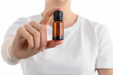 Close up photo of woman's hand holding a small jar of essential oils or another vitamins drops or...