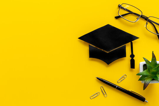 Graduation Hat On Students Table. Masters Or Bachelors Degree Concept