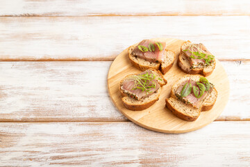 Bread sandwiches with jerky salted meat, sorrel and cilantro microgreen on white. side view, copy space.