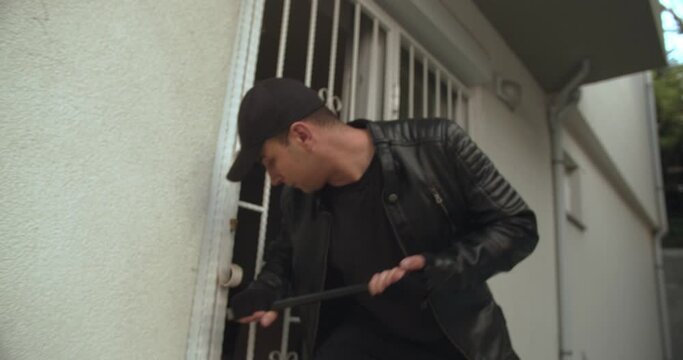 Thief with crowbar entering a house