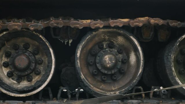 Moving shot of destroyed rusty soviet tank caterpillar. Close up of a demolished continuous band of treads of a burnt down self-propelled artillery installation. Wrecked tank continuous track

