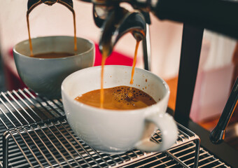 Close-up of espresso pouring from coffee machine flowing into the coffee cup make coffee for customers in the cafe.