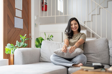 Portrait of smiling happy cheerful beautiful pretty asian woman relaxing on cozy sofa