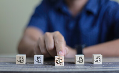 man pushing wooden block cube which print screen protect covid and alcohol gel icons for healthy and wellness concept.