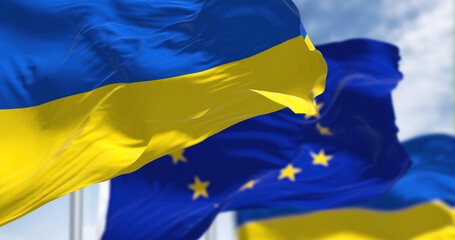 the national flag of Ukraine waving with blurred european union flag on a clear day