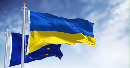 the national flag of Ukraine waving with blurred european union flag on a clear day