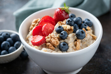 Oatmeal porridge bowl with blueberries, strawberries and nuts. Closeup view bowl of healthy breakfast oats