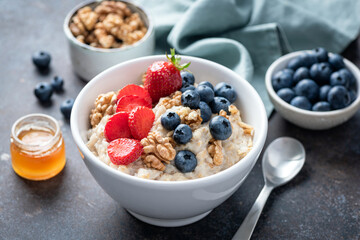 Breakfast oatmeal porridge bowl with berry fruits and walnuts. Healthy high fiber meal