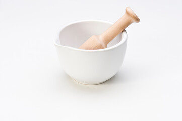 White ceramic mortar with a wooden pestle, isolated on white