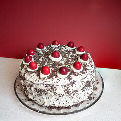 black forest cherry cake on a mottled table, red background with copy space