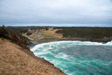 An aerial view of Middle Cove Beach with waves rolling onshore. There are small farmhouses with...