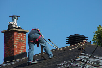 man on roof working to remove shingles roofer construction worker - obrazy, fototapety, plakaty