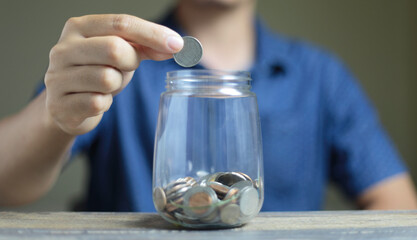 Businessman hand putting coins in glass jar. Concept of saving money, financial planning, investment, growth management, business, financial.
