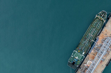 Aerial top view oil tanker ship at oil terminal industrial port for transfer crude oil to oil refinery, Business import export oil and gas petrochemical.