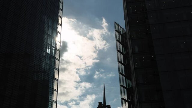 Airplane Flight Over Business Center Of Skyscrapers At London. Bottom View Of High-rise Buildings With Flying Plane In Blue Sky With Clouds in Afternoon. Air Transport, Travel, Vocation concept.