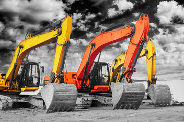 Powerful excavators at a construction site against a cloudy evening sky. earthmoving construction equipment. Lots of excavators.