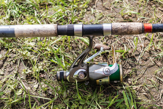 Fishing spinning lies on the grass. Fishing with a spinning reel. Close-up of fishing tackle.