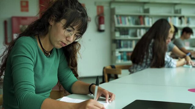 Young woman learing inside library at university school	