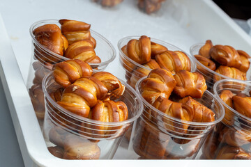Portion size clear plastic containers filled with soft crispy golden brown bite size pretzels. The...