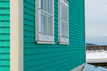 Two double hung windows on a green exterior wall of a vintage style building. The building has...