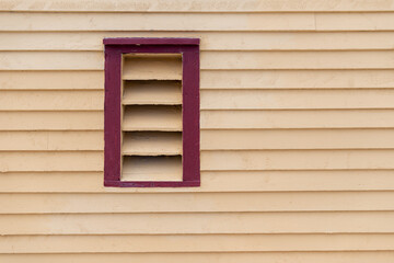 The exterior of a vintage yellow wooden wall is covered in horizontal beveled cape clapboard...