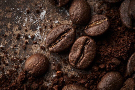 Roasted coffee beans different sort ground and whole isolated close up on brown grunge background © amixstudio