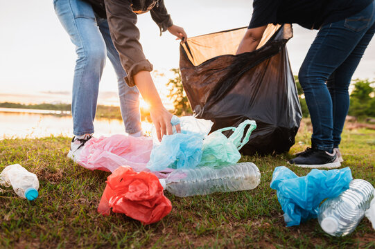 woman hand picking up garbage plastic bag for cleaning at park