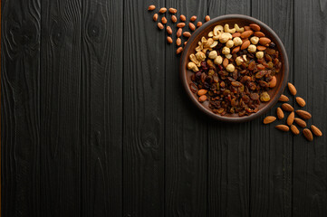 Hazelnuts, cashews, raisins, almonds, peanuts, walnuts on a wooden black background