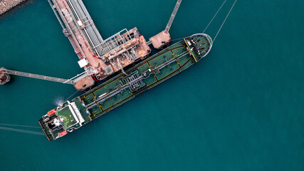 Aerial top view oil tanker ship at terminal industrial port for transfer crude oil to oil refinery, Business import export oil and gas petrochemical.
